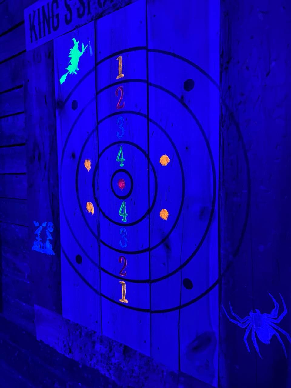 Painted axe target glowing under blacklights at King's Sport Axe House